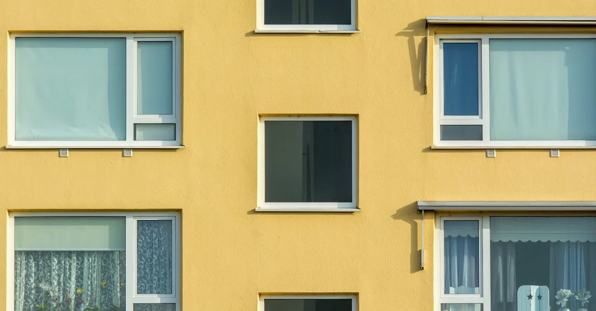 Exterior view of a modern apartment building with balconies and a tree, showcasing urban architecture.