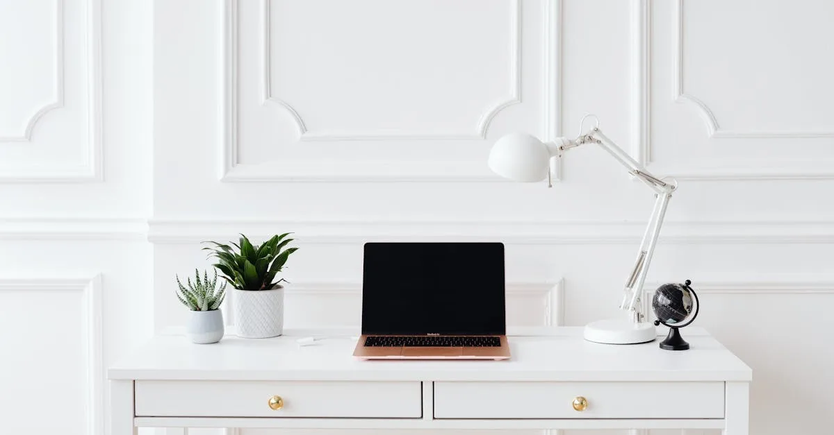 A sleek office setup featuring a laptop, notebooks, and chairs on a white desk.